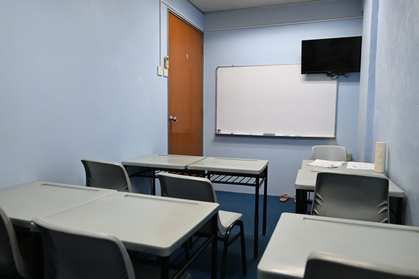 Desks facing a whiteboard and screen